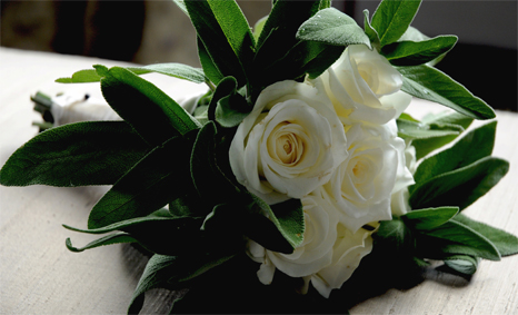 Handtied bouquet of white roses surrounded in sage
